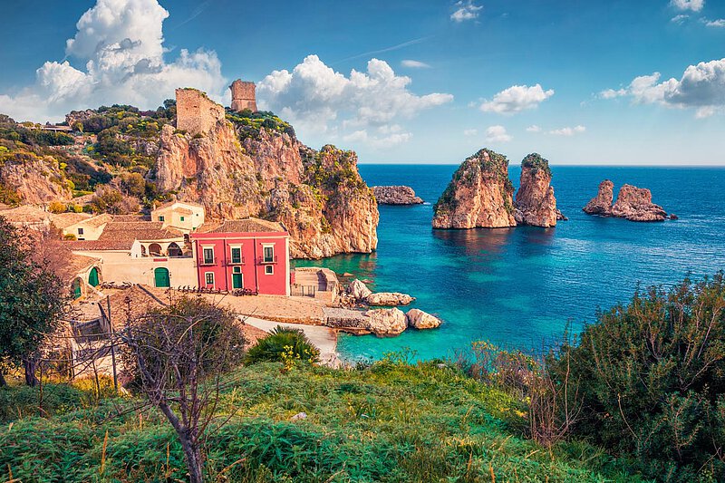 Küstenblick von Italien Eine lebendige Küstenlandschaft in Italien, die bunte Gebäude am Ufer zeigt, umgeben von felsigen Klippen und klarem blauen Wasser, mit entfernten Inseln und einem teilweise bewölkten Himmel.