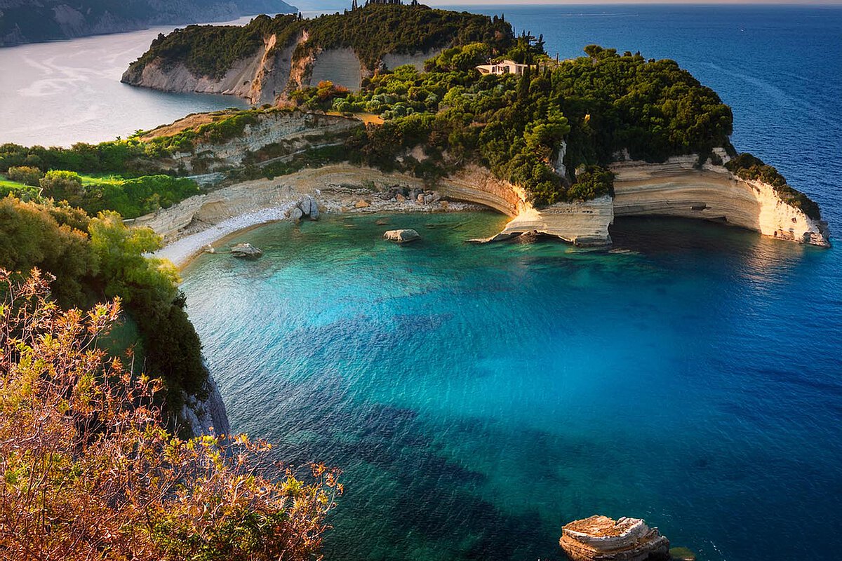 Scenic coastal view in Corfu, showcasing turquoise waters, rocky cliffs, and lush vegetation.