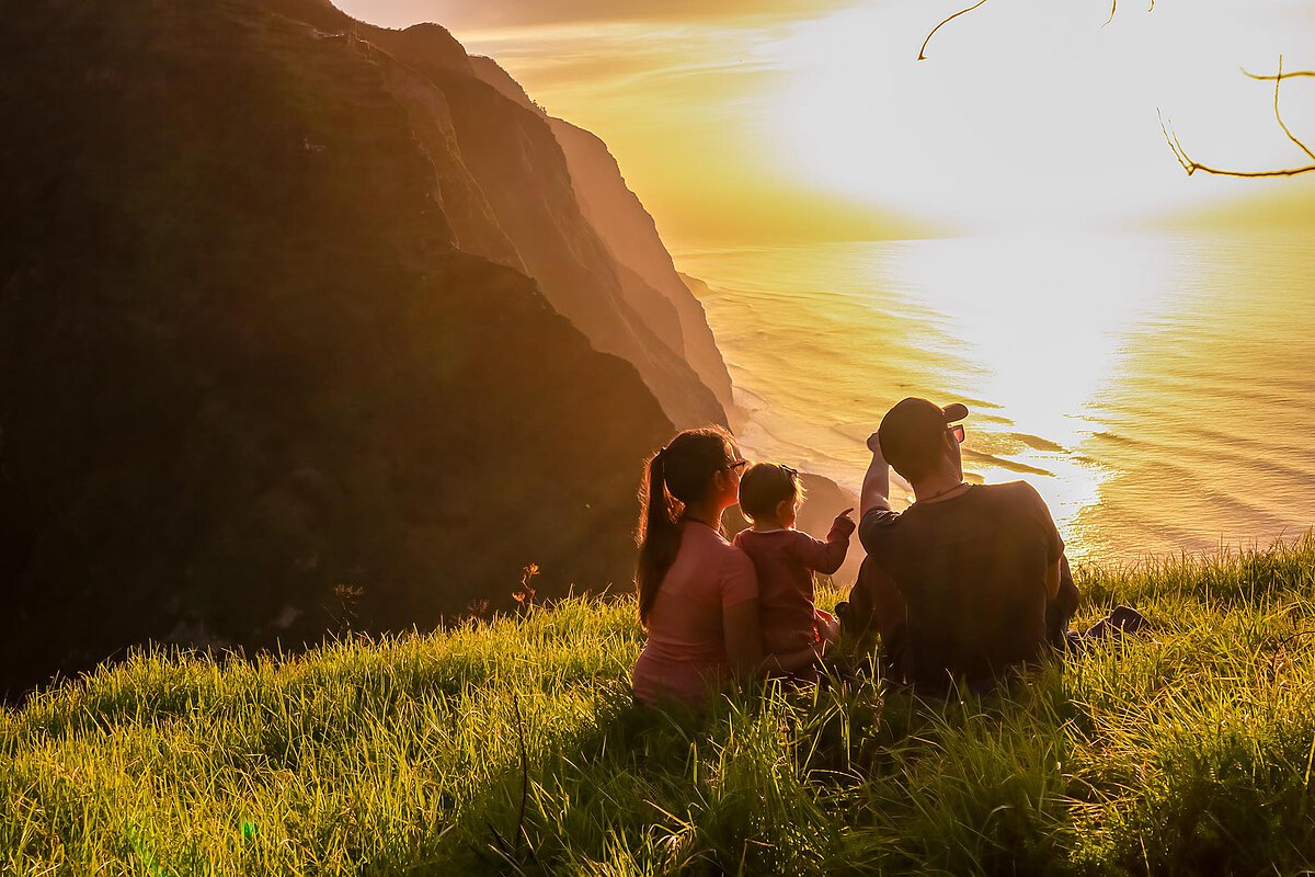 Family with child watching sunset on Madeira island.